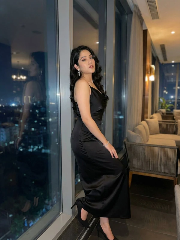 Woman in a black evening gown beside night-time windows