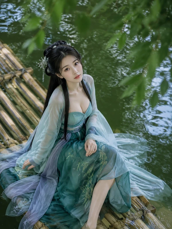 Woman in green traditional clothing seated on a bamboo raft